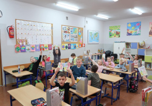 Uczniowie w sali klasowej kolorują laurki.