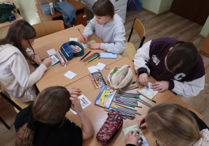 Uczniowie w sali klasowej kolorują laurki.